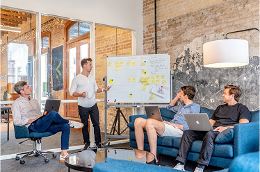 thumbnail-seo-teams people meeting in a lounge, looking at a whiteboard